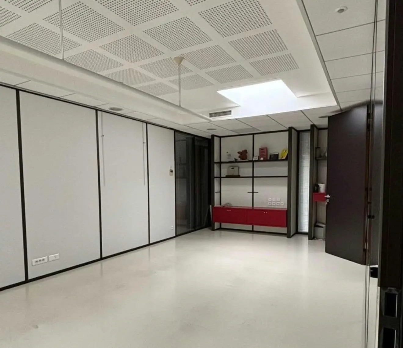 Sala de oficinas terminada con techo acústico perforado y lucernario