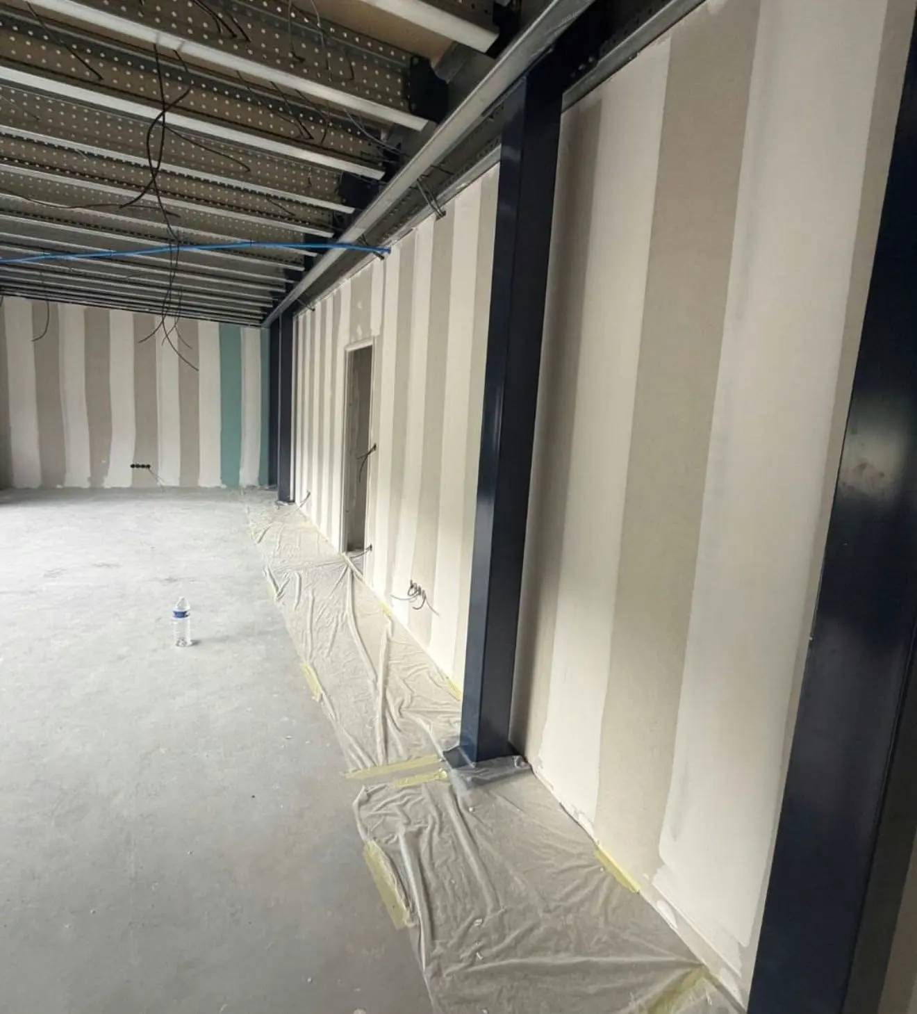 Interior bajo la entreplanta: tabiques PYL con juntas tratadas, pilares metálicos y el cableado de instalaciones preparado en el forjado