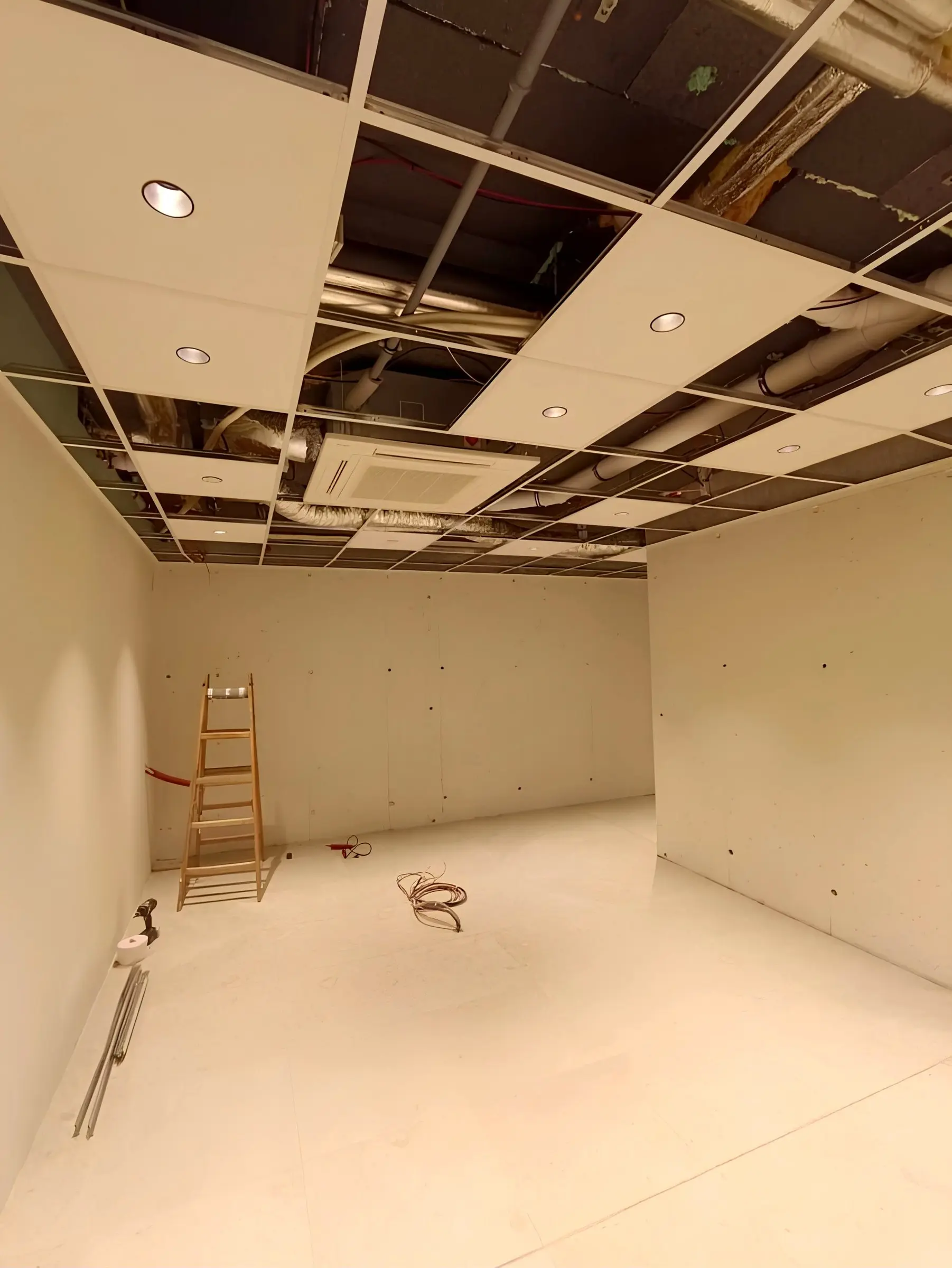 Local comercial en obra con la perfilería del techo registrable montada, placas a medio colocar e instalaciones de climatización a la vista