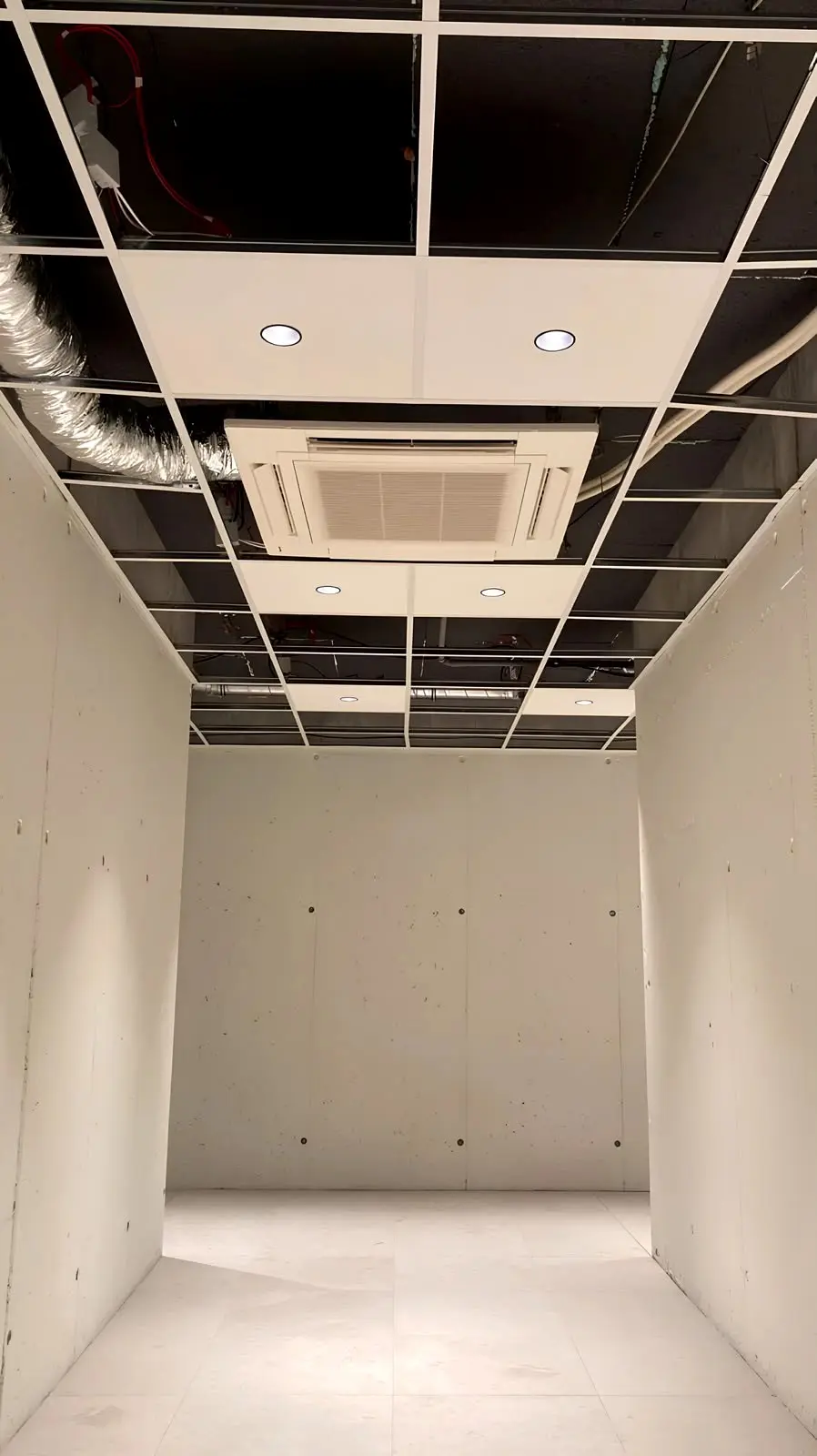 Cierre del techo registrable del local: casete de climatización ya instalado y placas pendientes en parte de la retícula