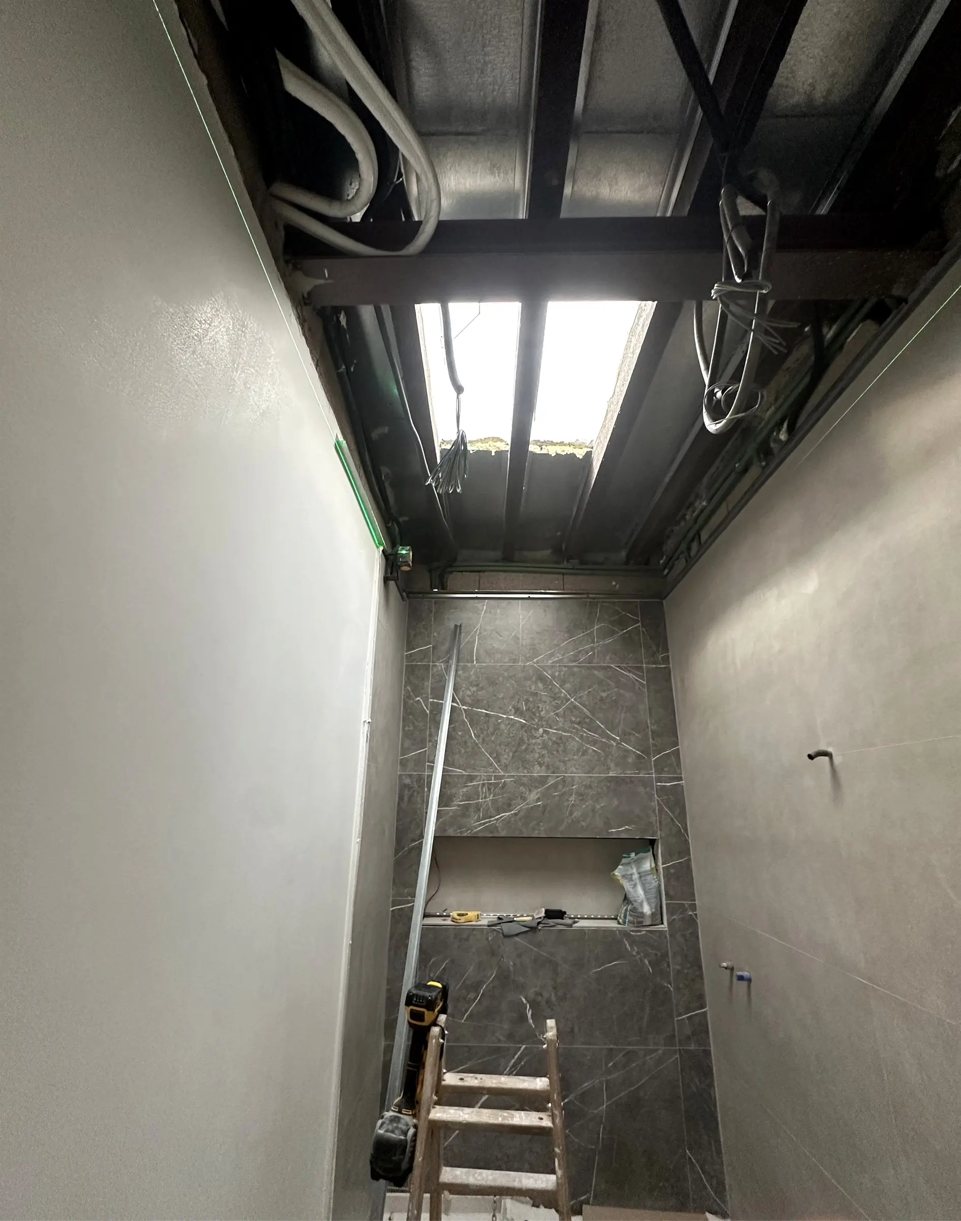 Baño en obra con la estructura del techo abierta alrededor del lucernario cenital, antes del cierre con placa