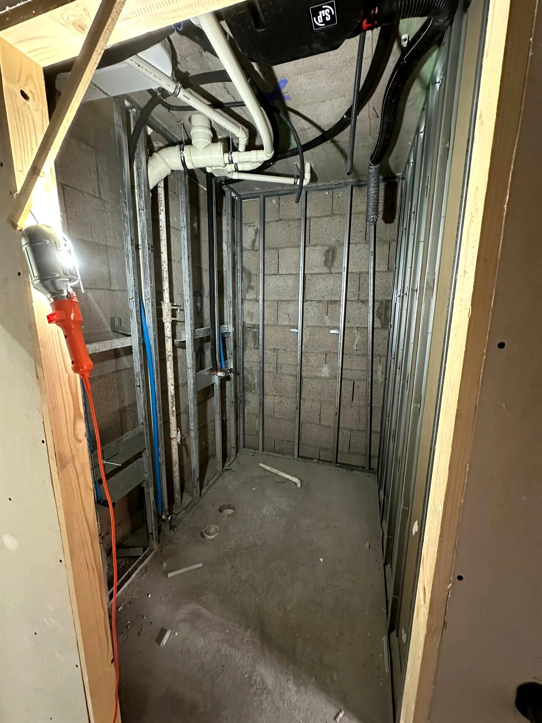 Cuarto técnico con la perfilería metálica montada sobre muro de bloque y las instalaciones de fontanería pasando por detrás
