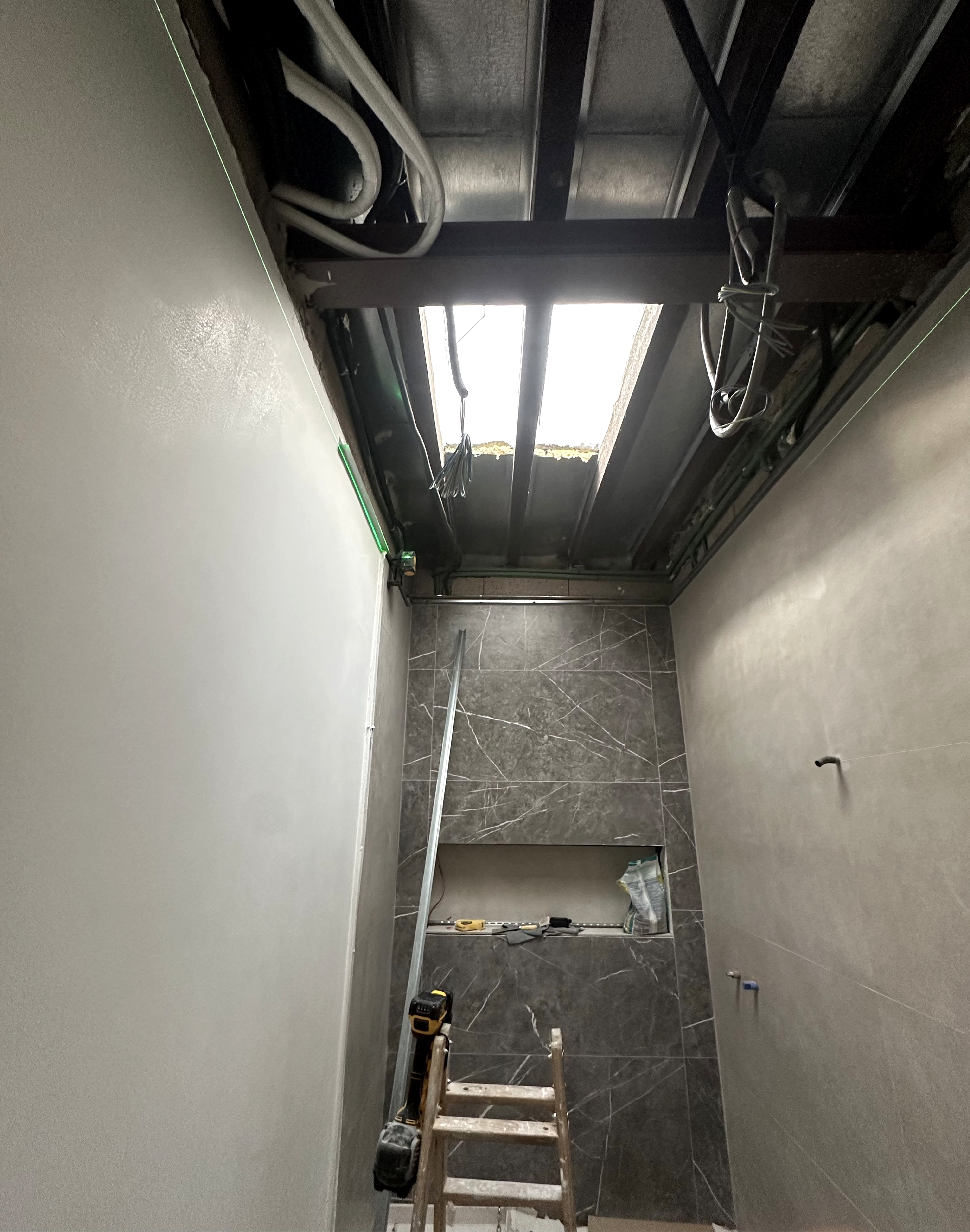 Baño en obra con estructura de techo abierta y tragaluz cenital antes del cierre PYL