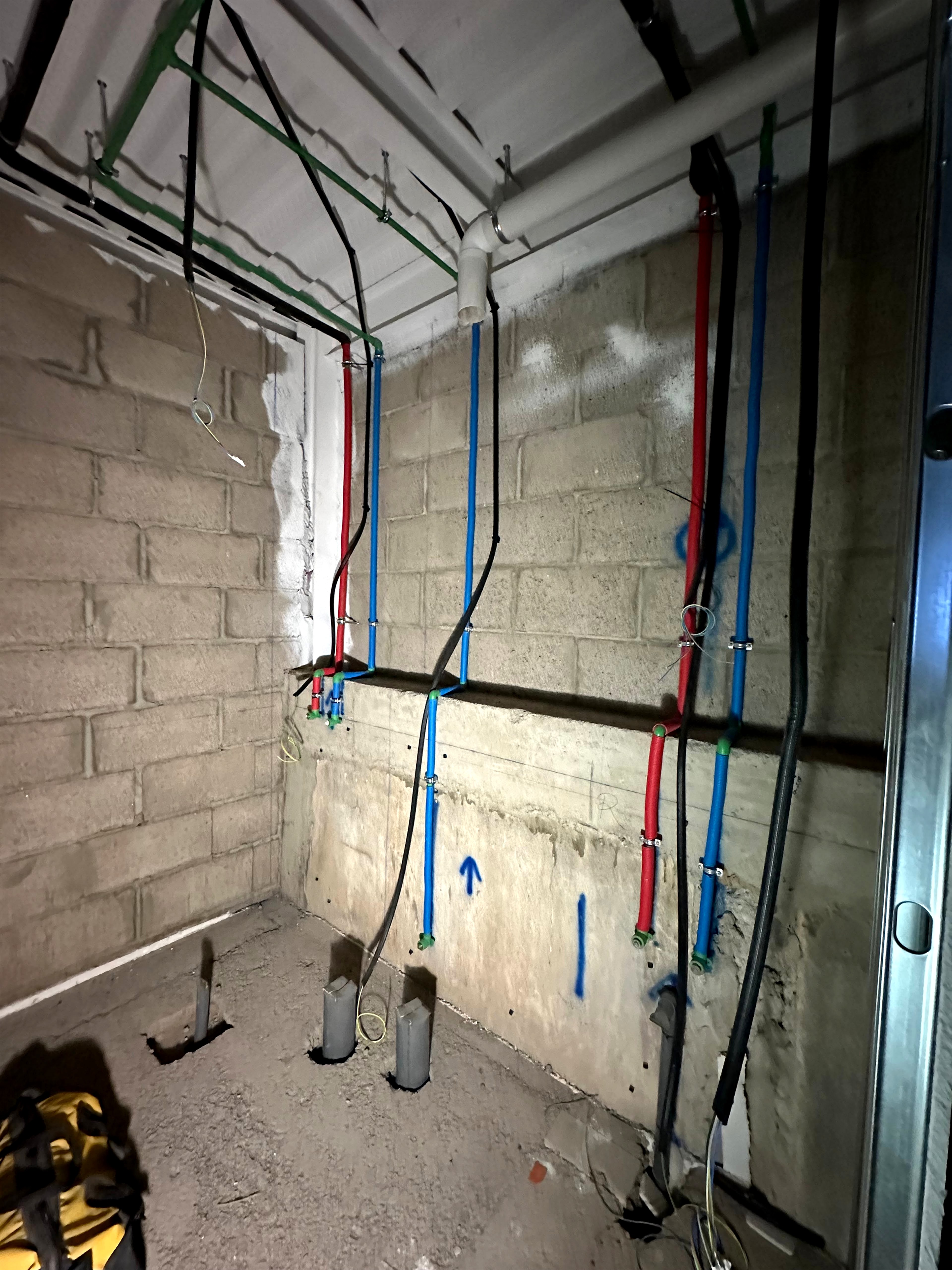 Antes · Cuarto técnico de vivienda con instalaciones de fontanería empotradas en muro de bloque y previsiones para sanitarios
