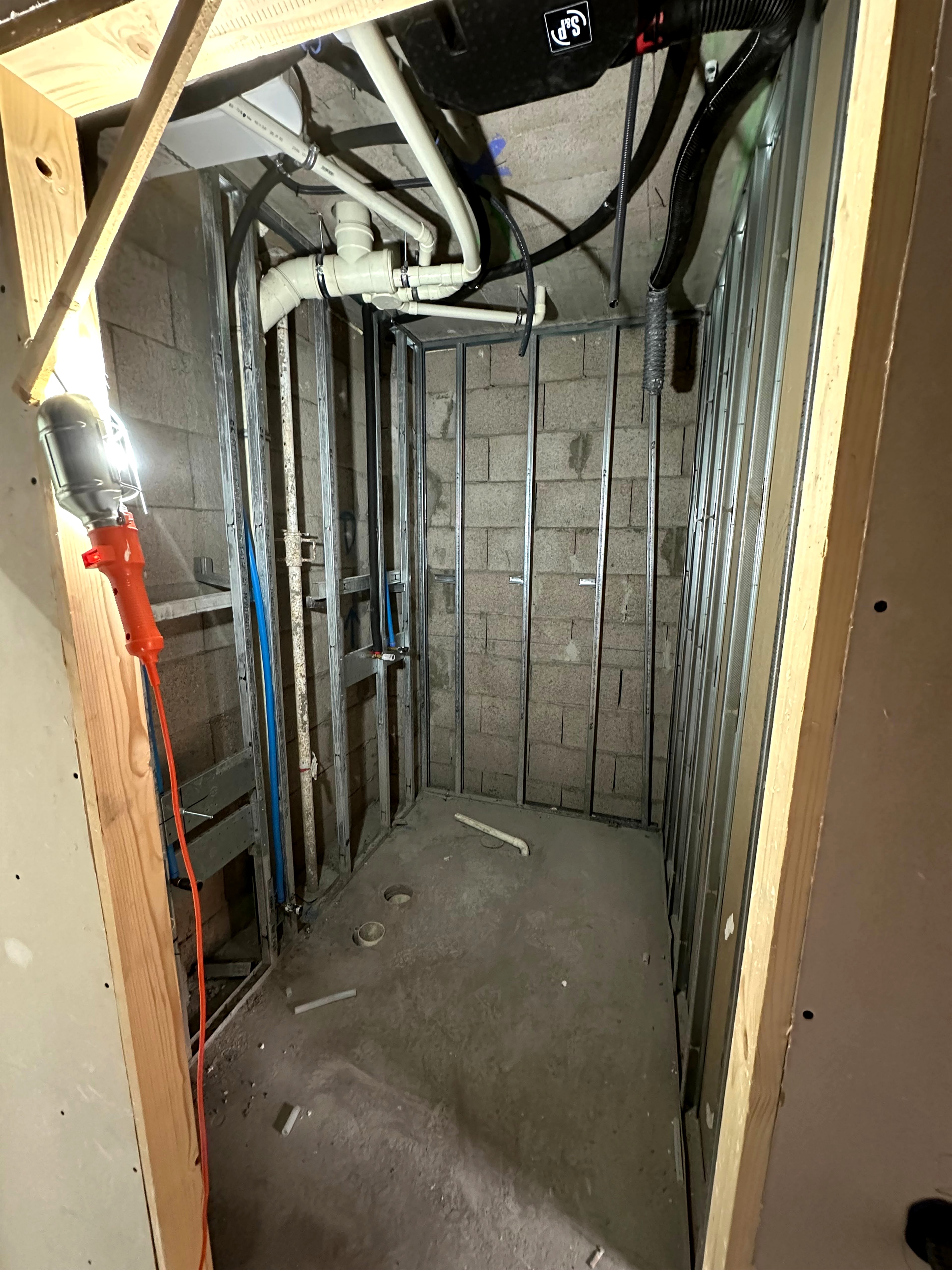 Cuarto técnico con perfilería metálica sobre muro de bloque, instalaciones de fontanería coordinadas